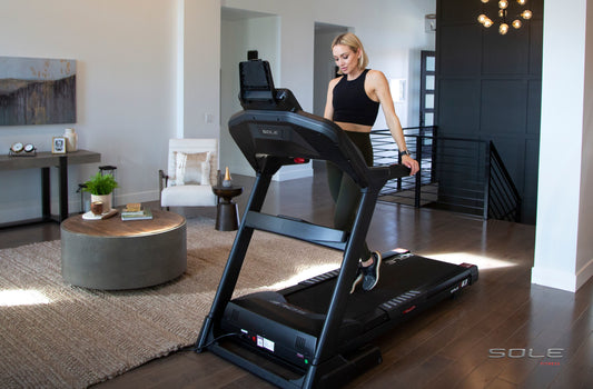 A women about to start running on a SOLE Fitness treadmill in a home environment.