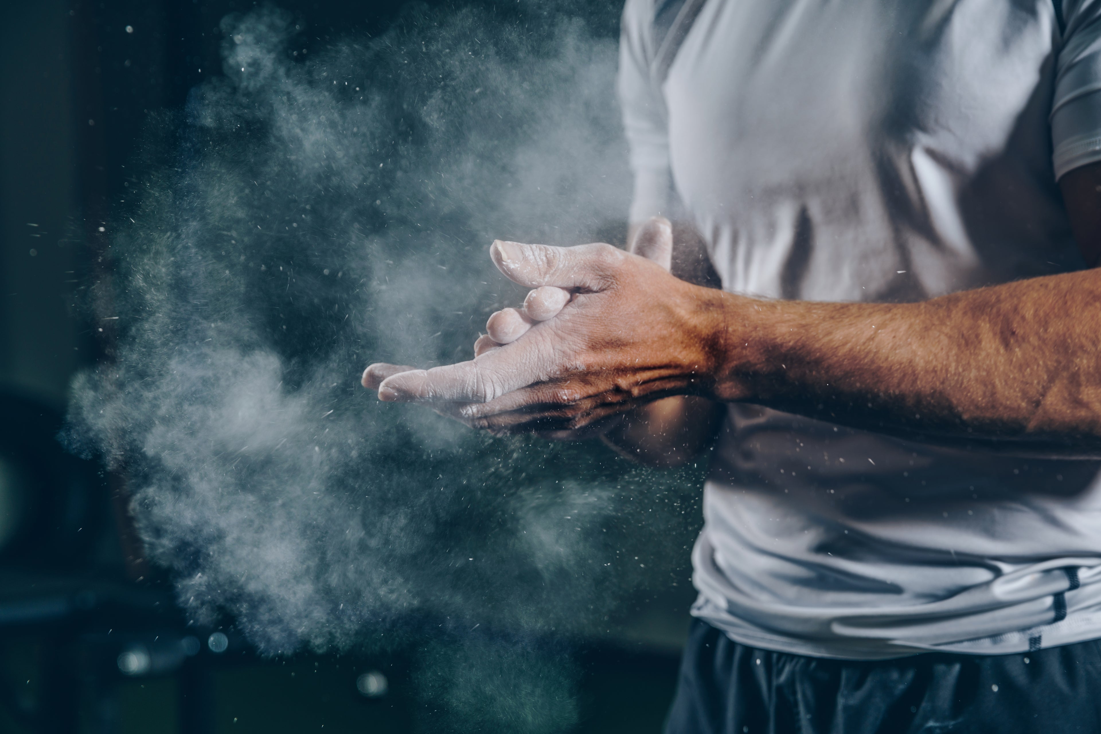 A man applies chalk to his hands for better grip before starting a gym workout.